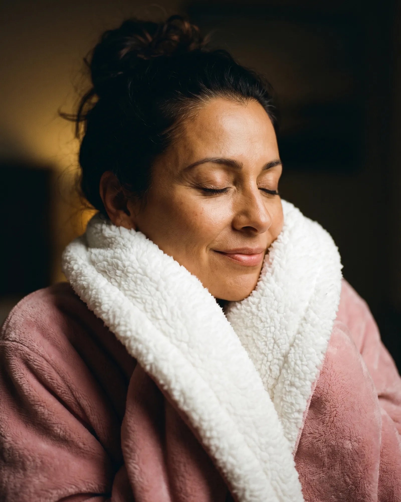 Woman with eyes closed, chin tucked into the sherpa collar of her Tovelle